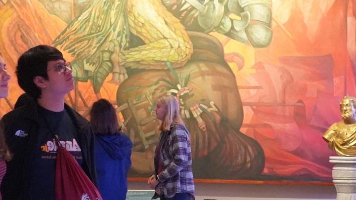 滚球网站的学生在画廊审阅一件大型艺术品.